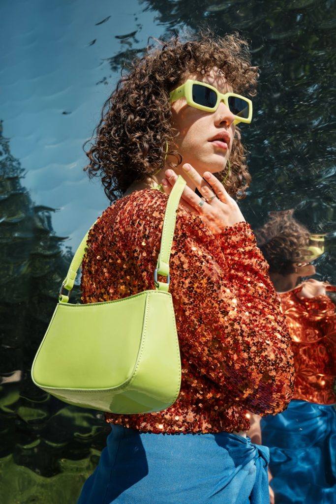 Frau mit lockigem Haar trägt eine  helle Handtasche.