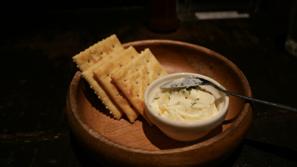 Ein Holzschälchen mit Cracker und einem Dip
